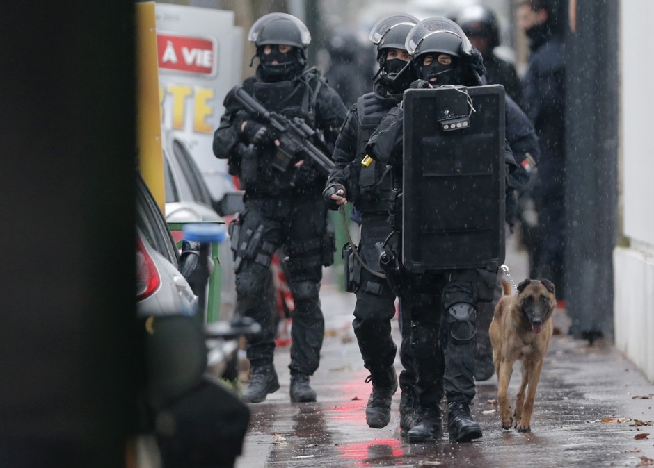 Armed French intervention police walk with a sniffer dog at the scene of a shooting of a policewoman in the street of Montrouge near Paris on January 8, 2015. 