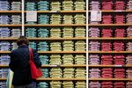 A customer stands in front of a display shirts in a variety of colors inside a Uniqlo store in Berlin.
