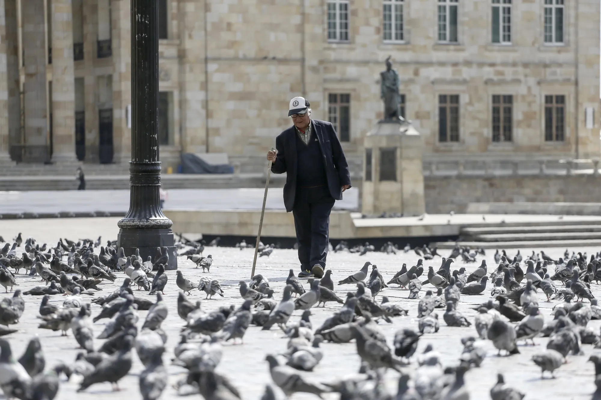A pedestrian walks past pigeons at Bolivar Square in Bogota, Colombia, on&nbsp;March 22.