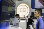 Attendees walk past signage for 5G at the Qualcomm Inc. booth at the Mobile World Congress Shanghai in Shanghai.