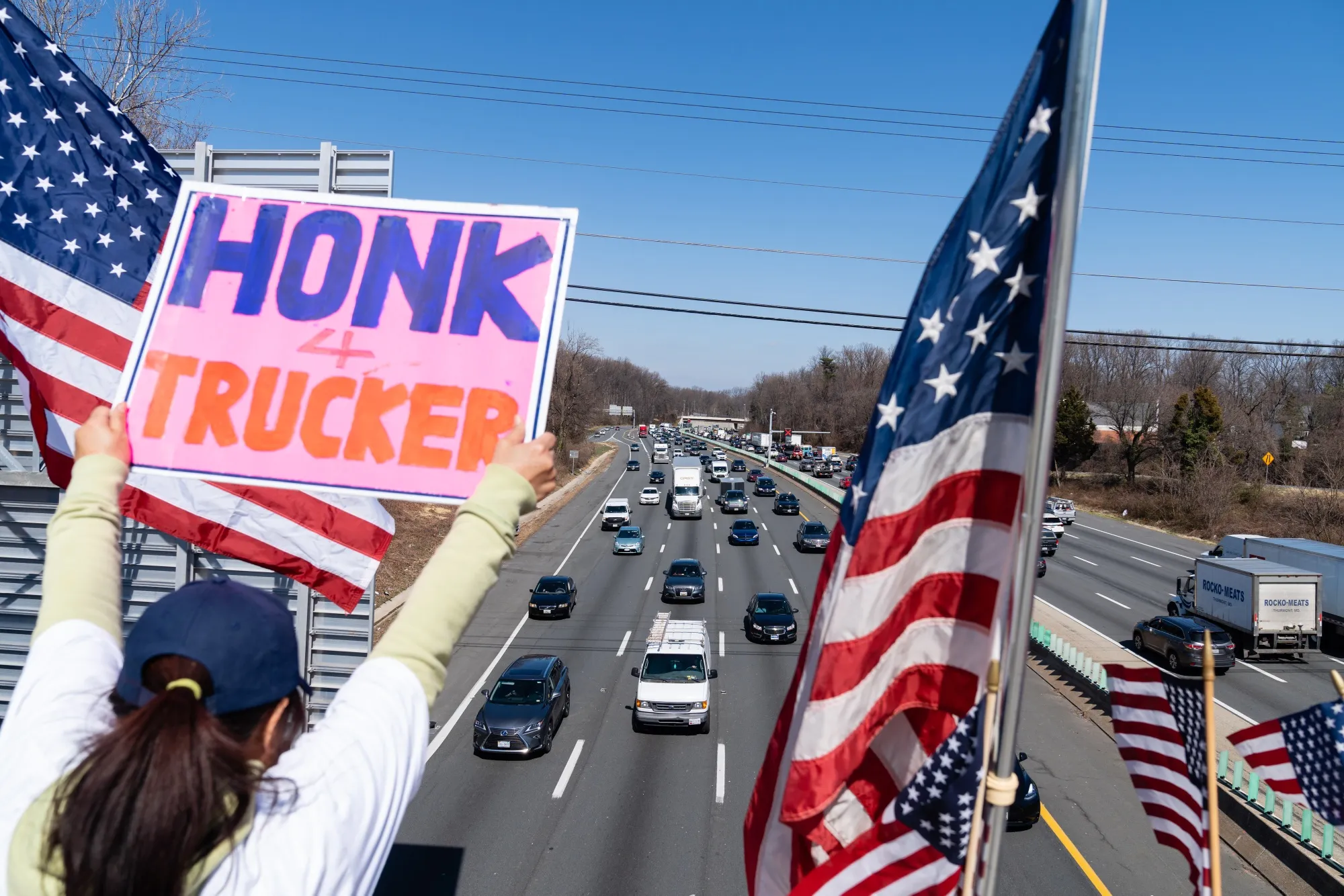 A supporter holds a sign while vehicles drive along Interstate 495 during The People’s Convoy” event in Georgetown Pike, Virginia, on March 11.