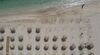 Aerial image of umbrellas on a sandy beach with clear green-blue waters