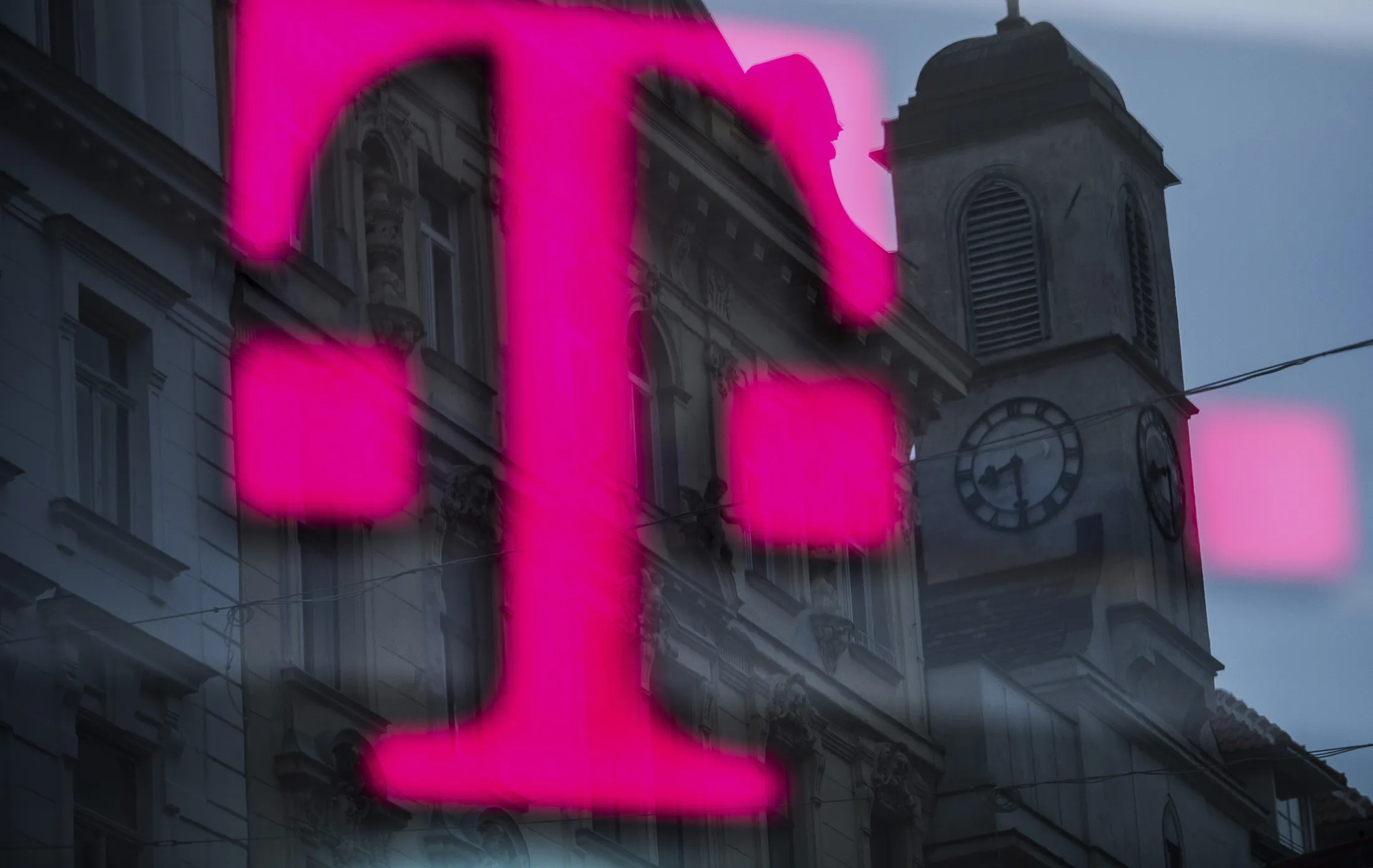 A clock tower is reflected in the window of a T-Mobile store, operated by Deutsche Telekom AG, in Vienna.
