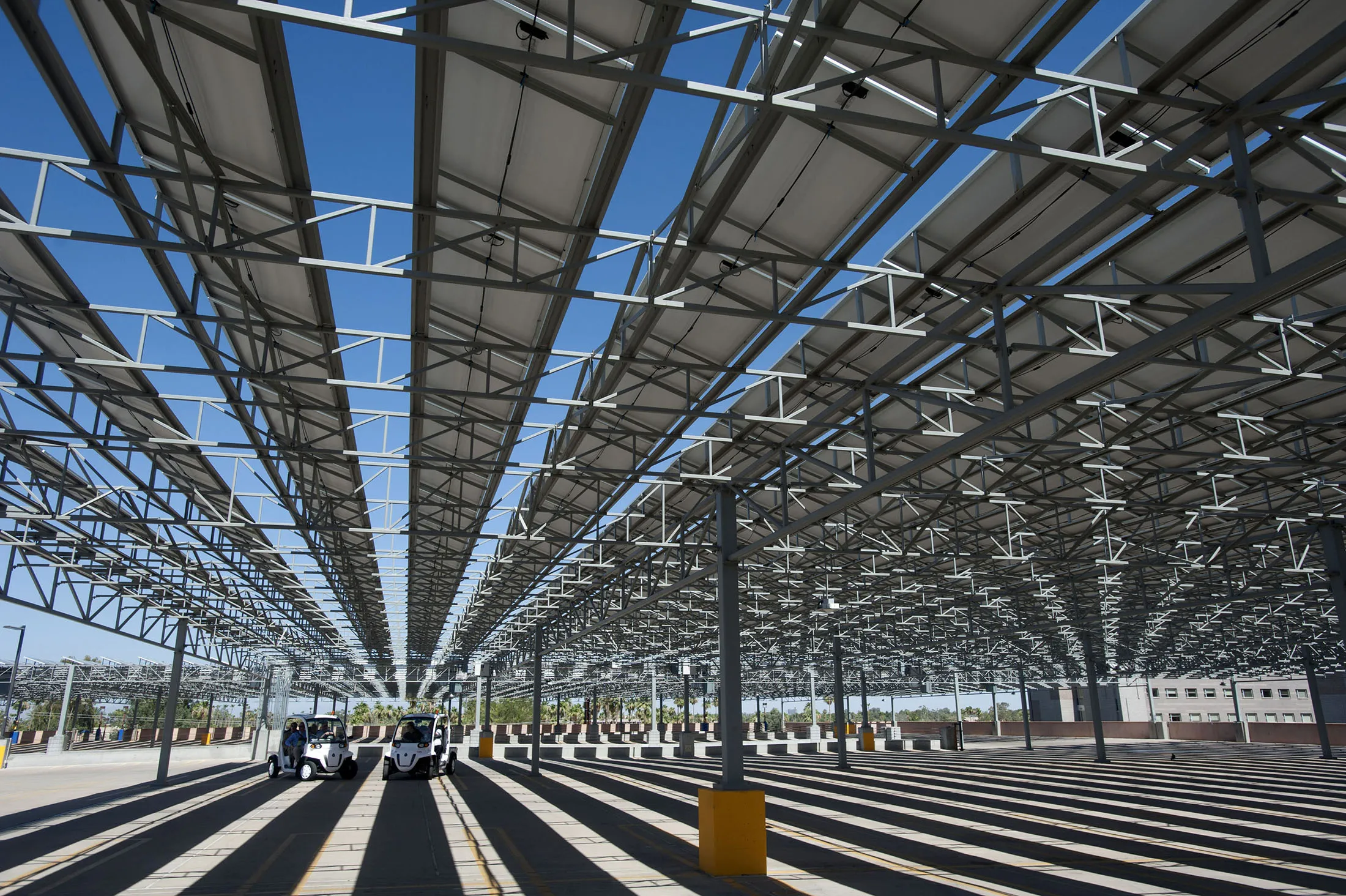 Golf carts stand under solar panels in a parking lot in Tempe, Arizona.
