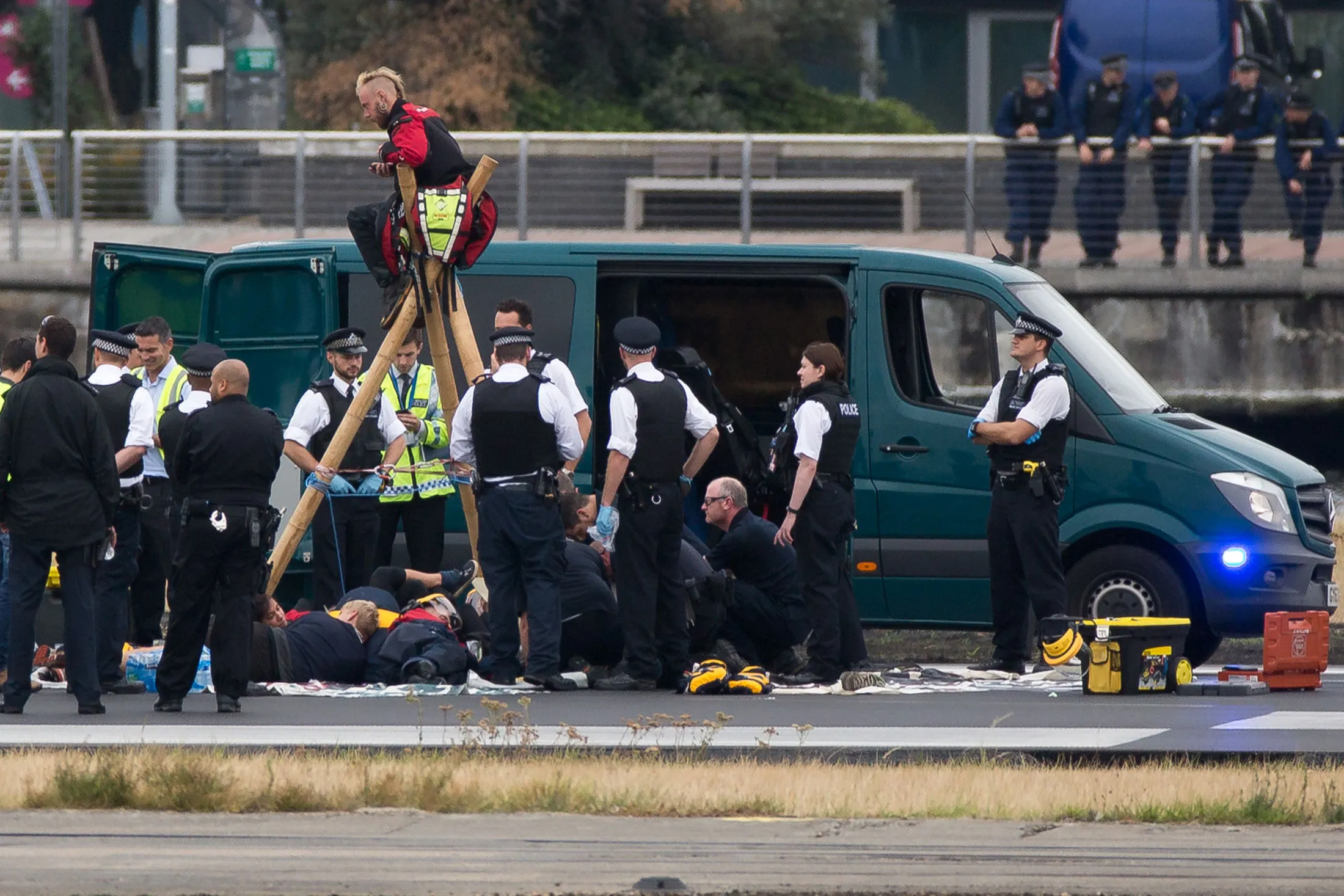 Emergency services surround protestors on the runway at London City Airport.
