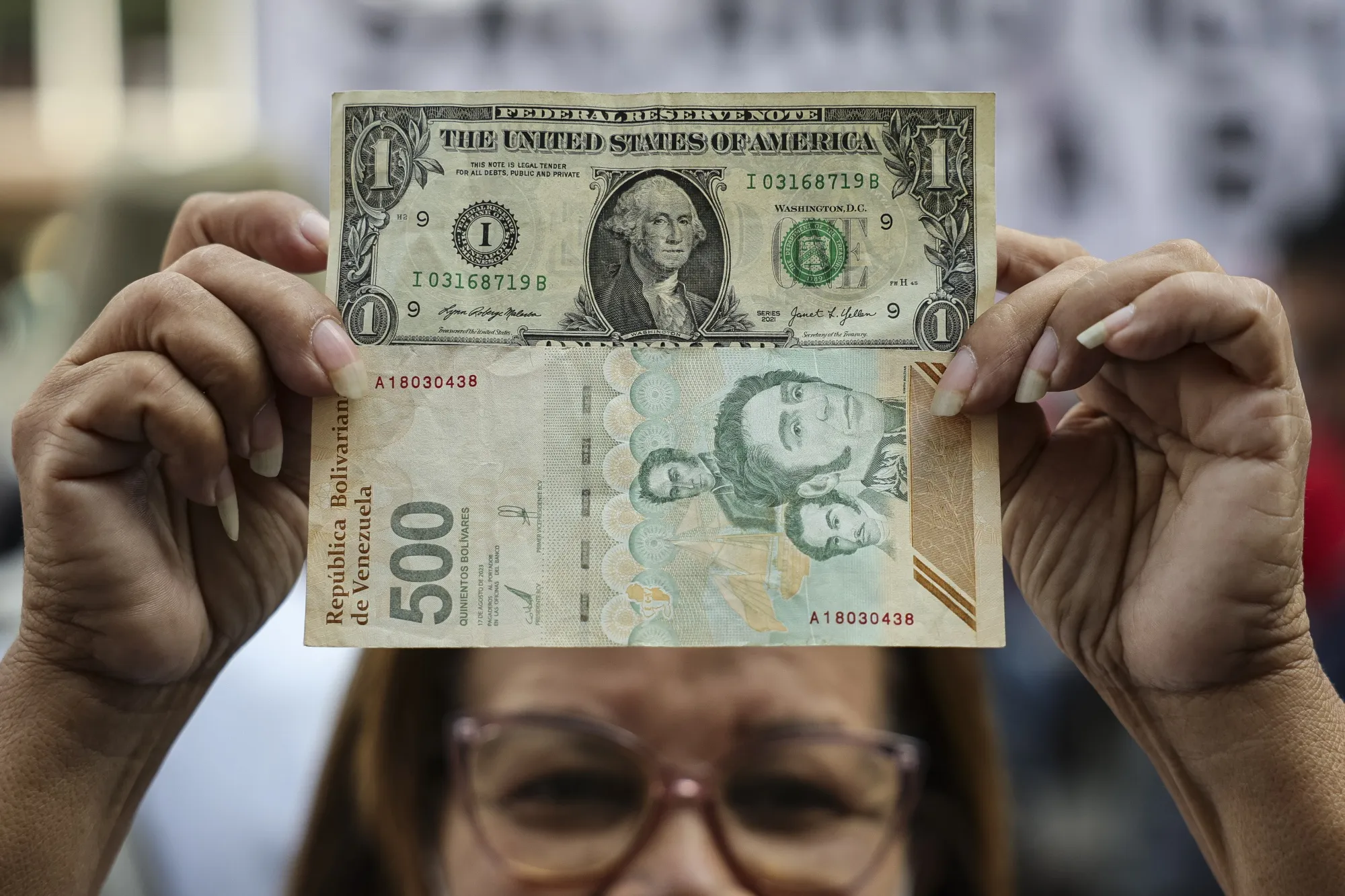 Una mujer sostiene un billete de US$1 y otro de 500 bolívares durante una manifestación en favor de un aumento salarial en Caracas, el 26 de febrero.