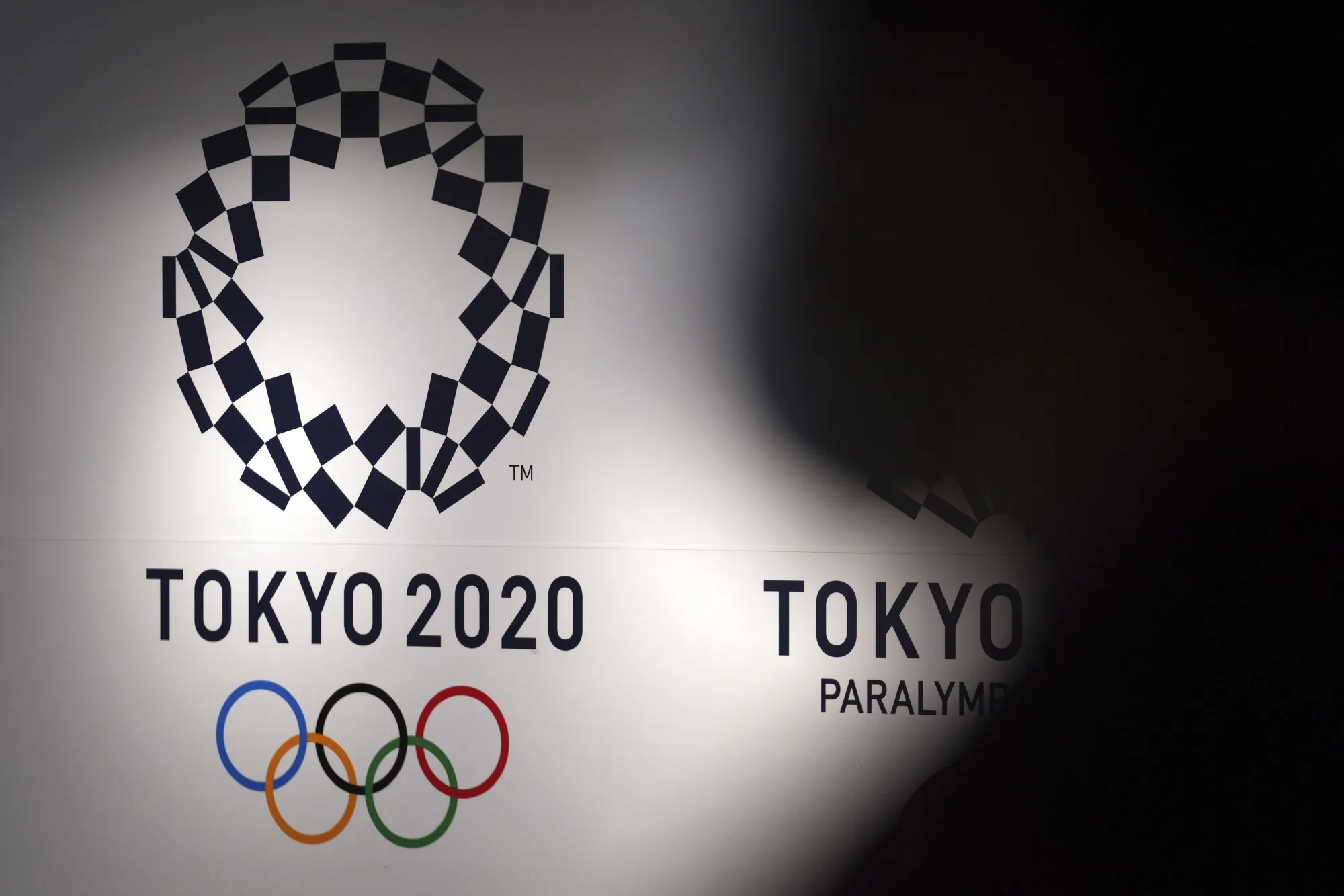 A person walks near Tokyo 2020 logo in Haneda Airport on June 14, 2021, in Tokyo. Tokyo Olympic officials, meeting Tuesday, June 21, 2022, before the body is dissolved at the end of the month, were to detail the final numbers that were driven up by the pandemic, but were in record range even before that. (AP Photo/Eugene Hoshiko, File)