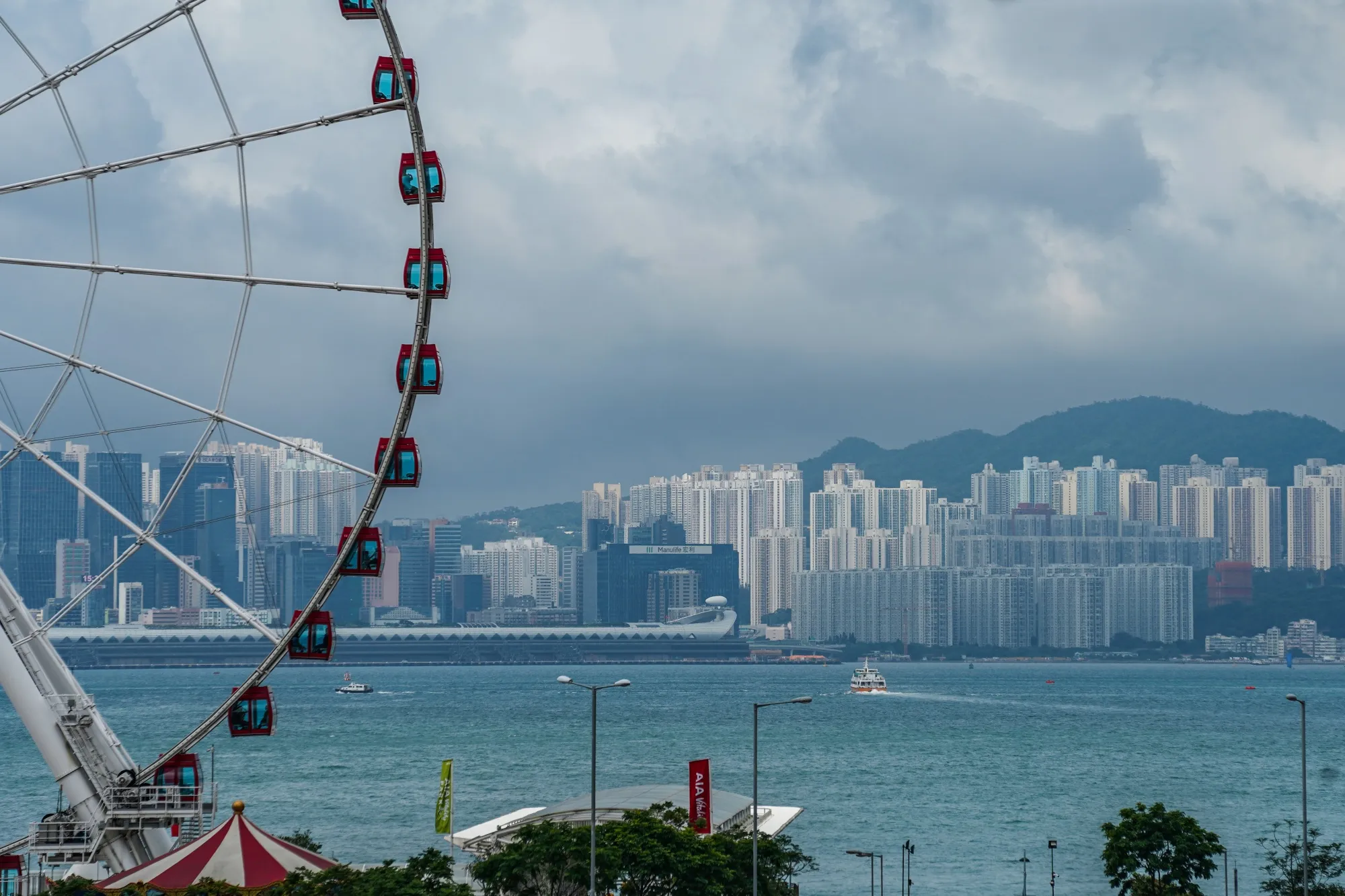 The Hong Kong Observation Wheel stands along the waterfront as buildings stand across Victoria Harbor in Hong Kong.