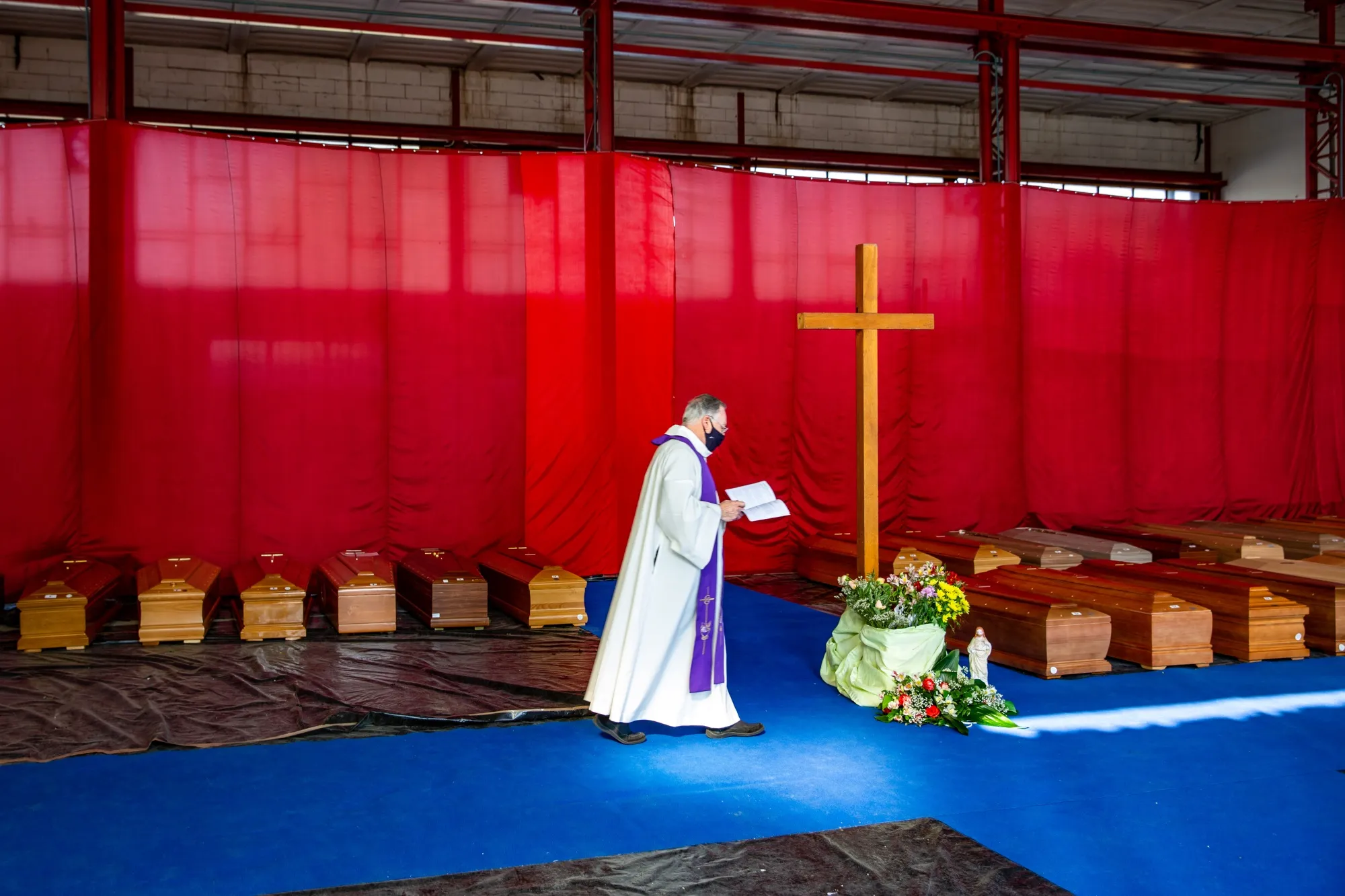 A priest, wearing a protective face mask, walks among coffins in Ponte San Pietro, near Bergamo, Italy, on April 3.