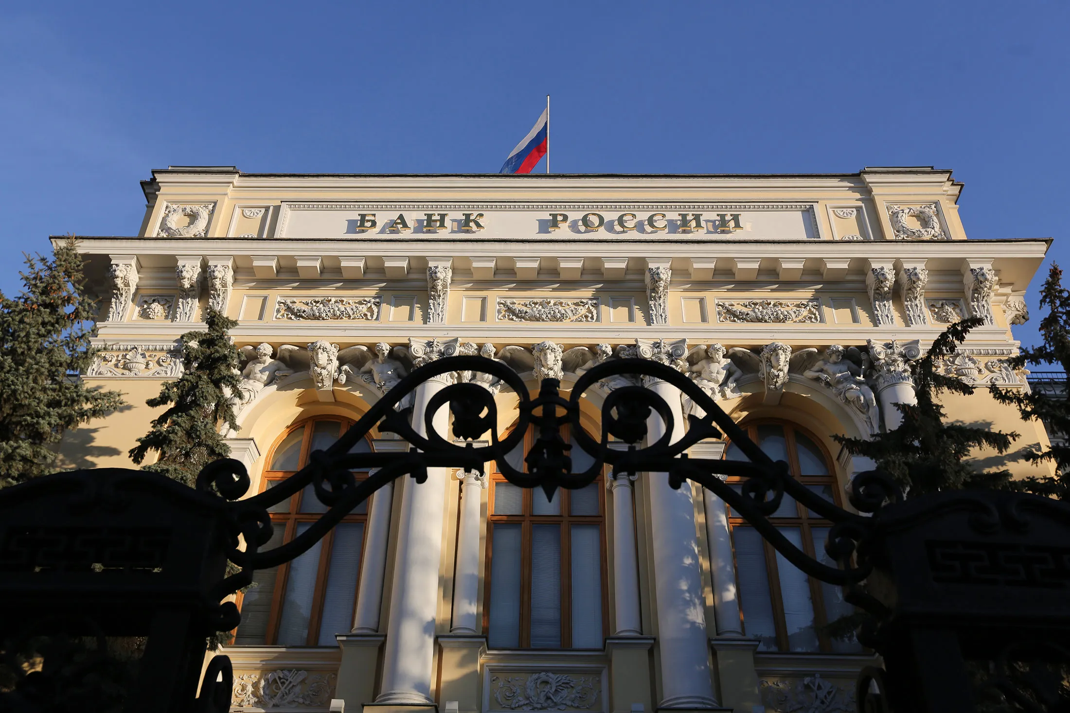 A Russian national flag flies above the headquarters of Bank Rossii, Russia's central bank, in Moscow, Russia, on Friday, Dec. 11, 2015. Russia's central bank left its benchmark interest rate unchanged for a third consecutive meeting as a slump in oil prices triggered a new bout of ruble weakness, raising the risk of faster inflation.
