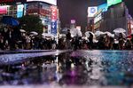 People walk along a street as rain falls in the Shibuya district in Tokyo.