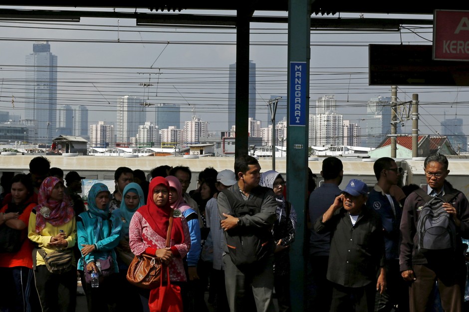 People wait for a commuter train at Manggarai train station in Jakarta