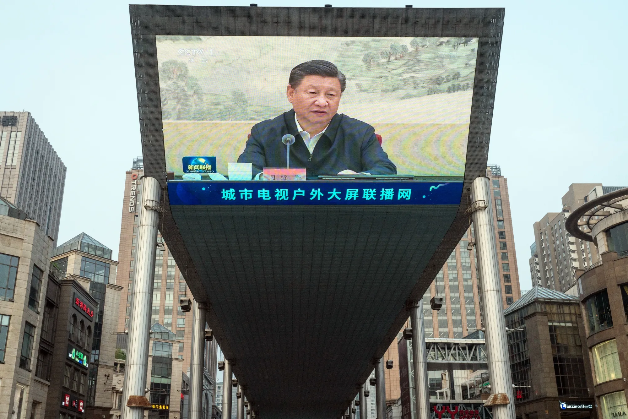 A screen shows a news broadcast of Chinese President Xi Jinping in Beijing.