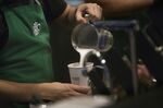 A barista pours frothed milk into a drink inside a Starbucks Corp. coffee shop in New York, U.S., on Monday, Jan. 18, 2016.