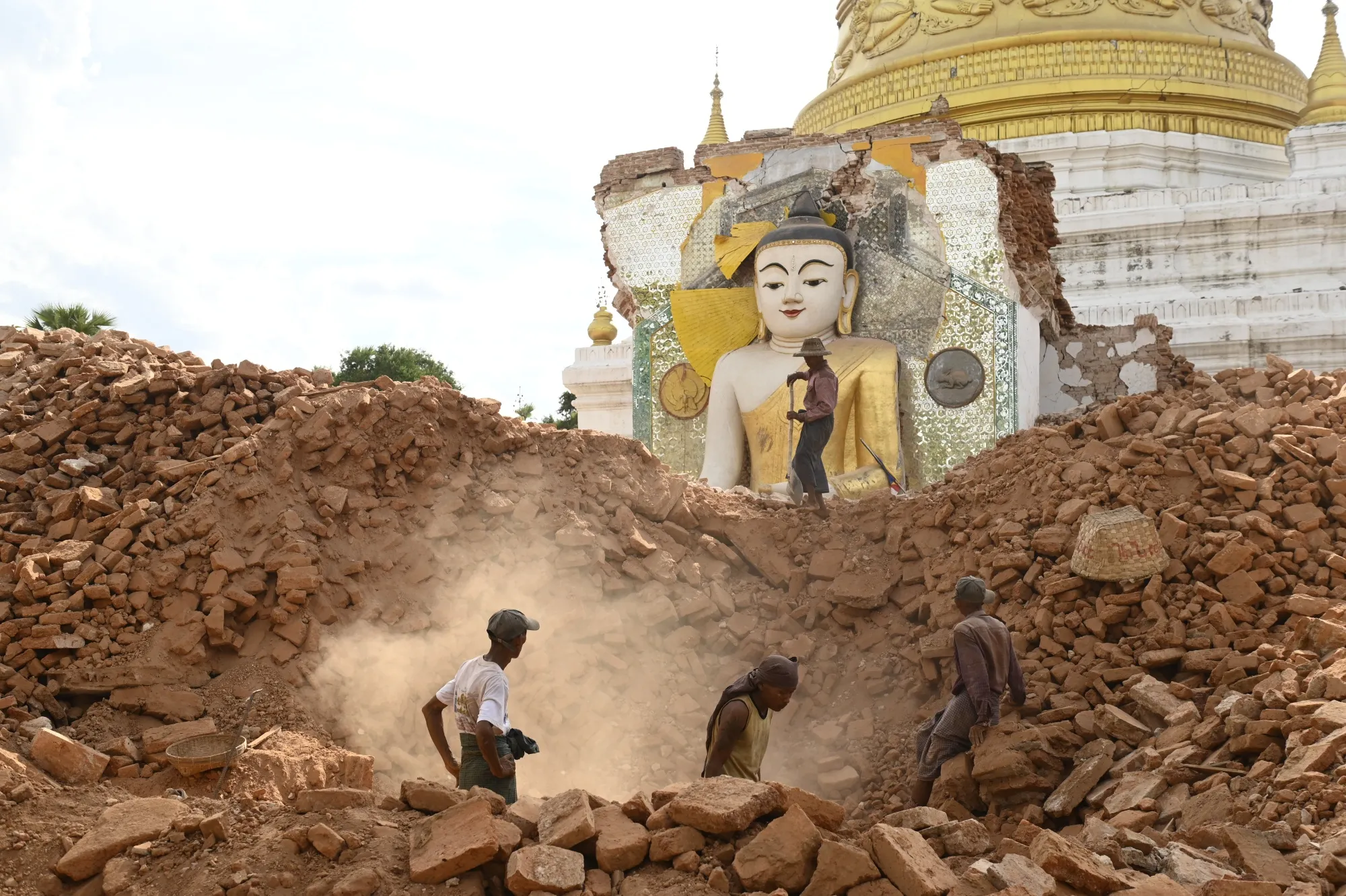 People clear debris of a damaged Buddha statue at Lawkatharaphu pagoda in Inwa, on the outskirts of Mandalay, on April 12.