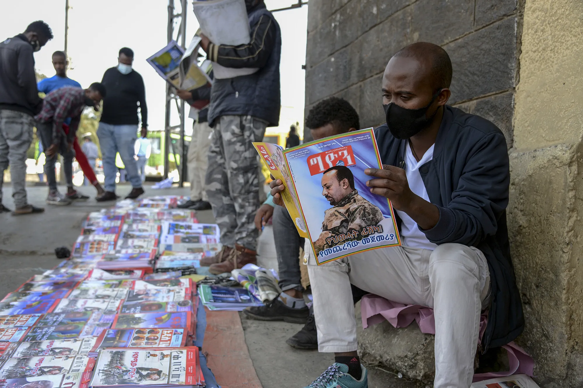 Ethiopians read newspapers and magazines reporting on the current military confrontation in the country, one of which shows a photo&nbsp;of Prime Minister Abiy Ahmed, on a street in&nbsp;Addis Ababa.