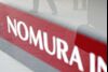 Businessmen are reflected on a sign of the Nomura Securities Co. in Tokyo, Japan, on Tuesday, Nov. 21, 2006.