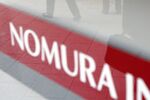 Businessmen are reflected on a sign of the Nomura Securities Co. in Tokyo, Japan, on Tuesday, Nov. 21, 2006.