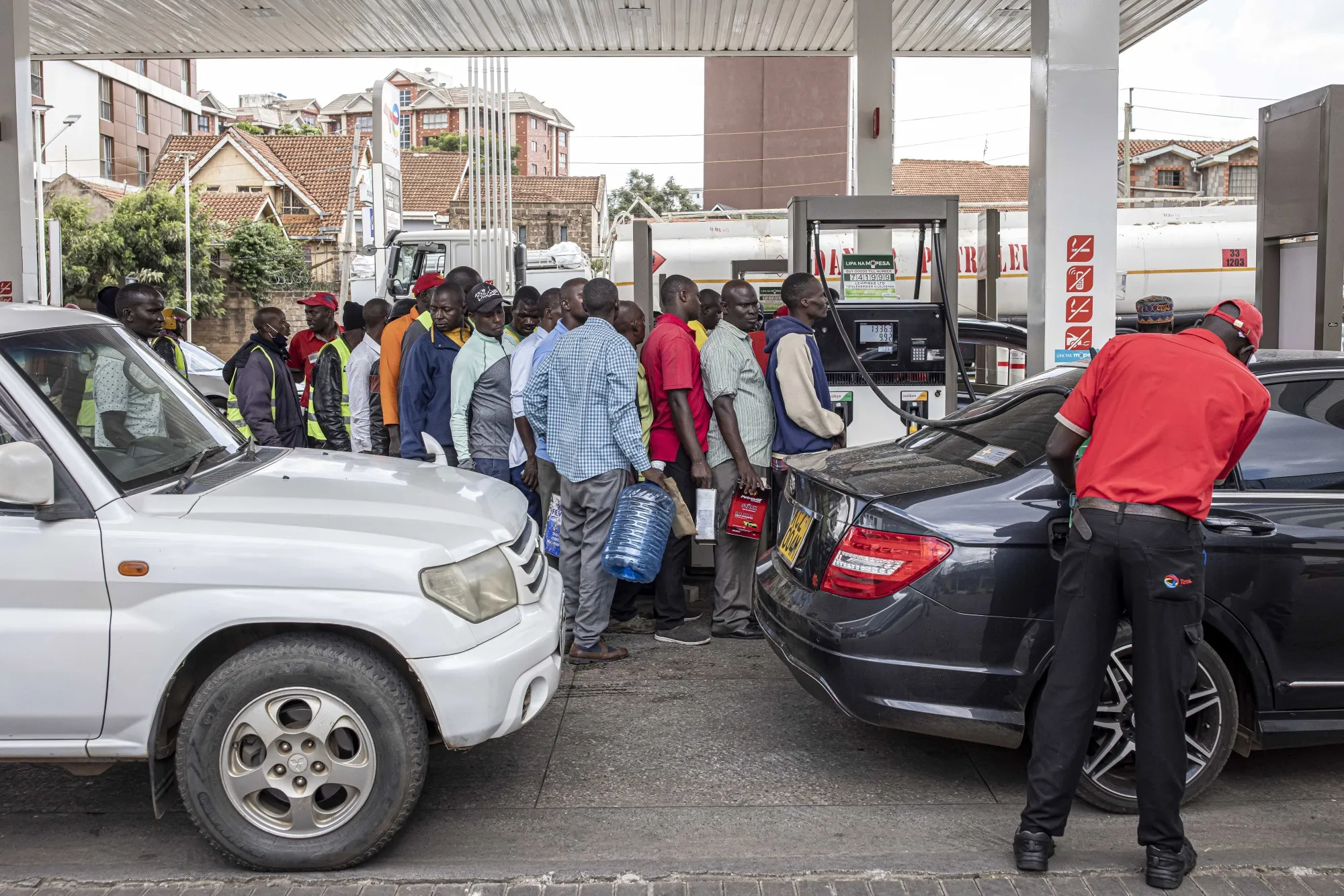 Drivers queue to fill cans with fuel at a gas station in Nairobi, Kenya, on&nbsp;April 13.&nbsp;To try curb inflation and ease pressure on currencies, Kenya and Tanzania have imposed measures, including subsidies on items such as fuel.&nbsp;