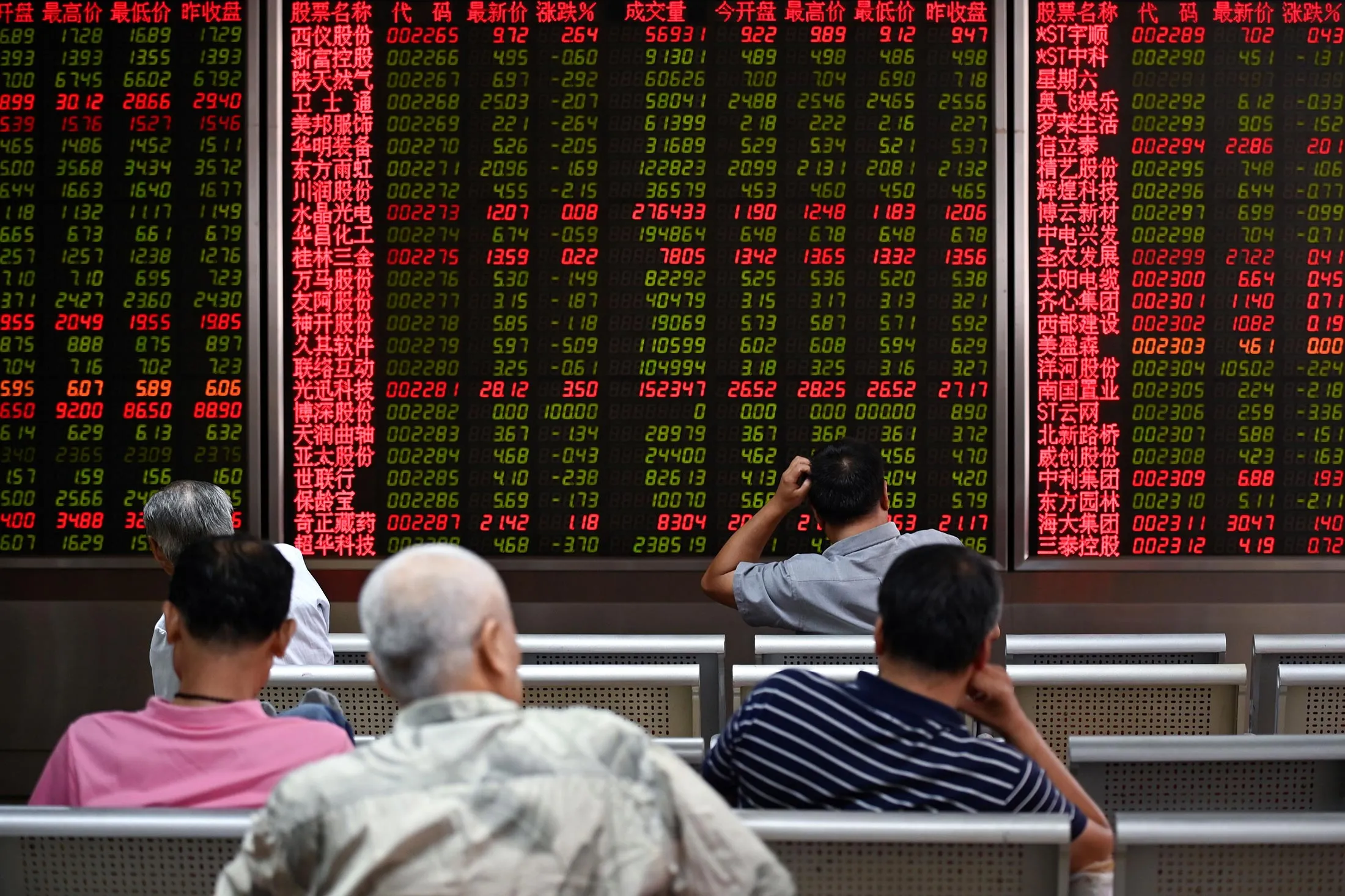 Investors sit in front of screens showing stock market movements at a securities company in Beijing.