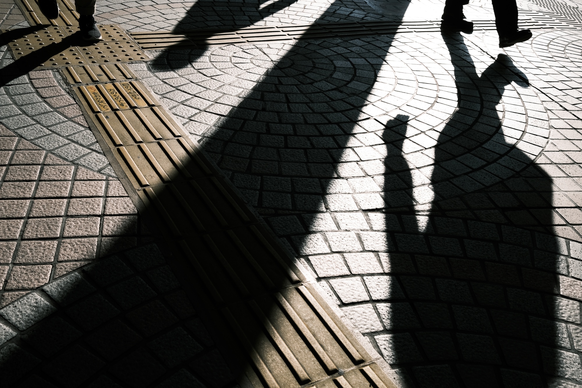 The shadows of commuters are cast on the ground in Tokyo.