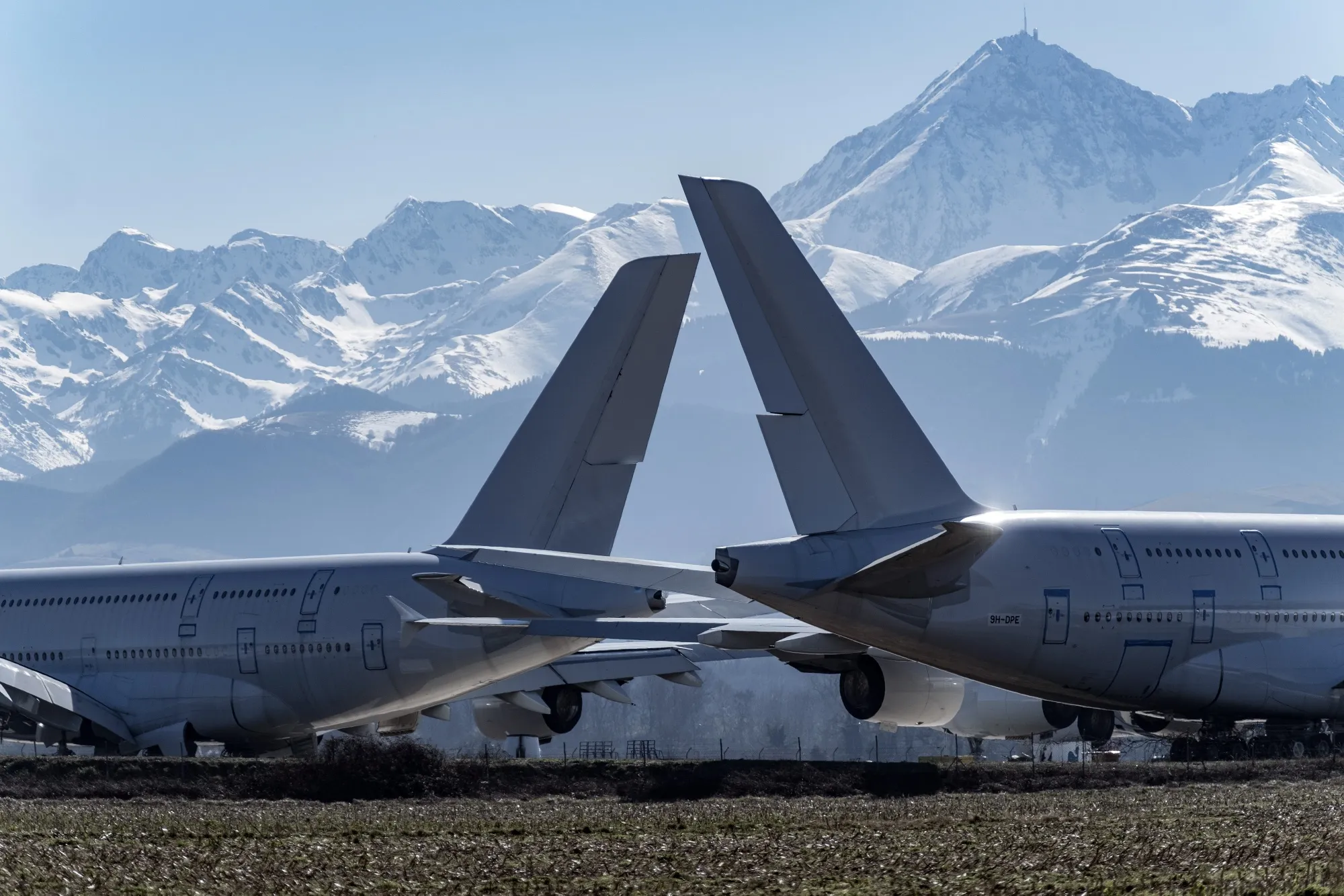 Two Airbus A380 aircraft sit on the ground at the Tarmac Aerosave SAS storage and recycling facility against a background of the Pyrenees mountain range in Tarbes, France in 2019.