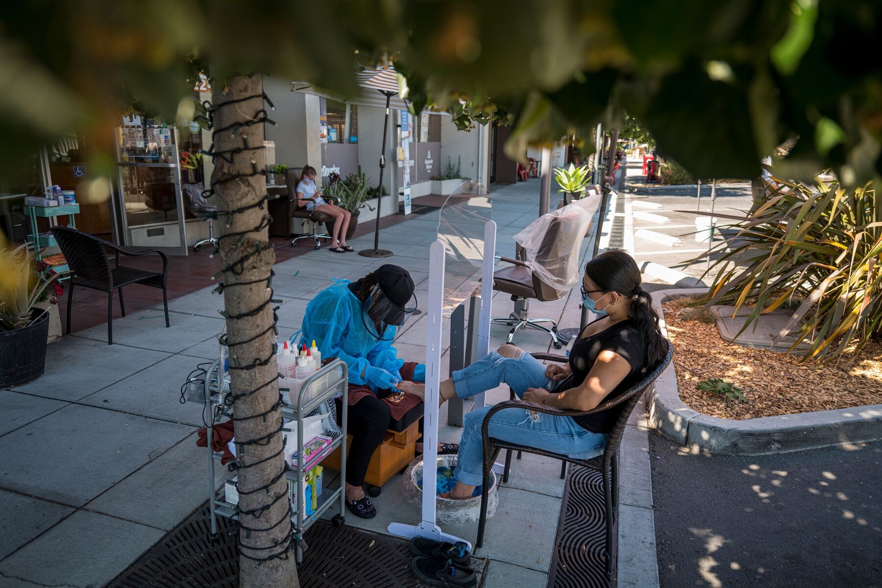A worker gives a pedicure to a customer outside of a nail salon in Palo Alto, California, on July 28.