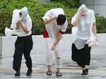 People walk against strong winds in Nagoya on September 4, 2018,.