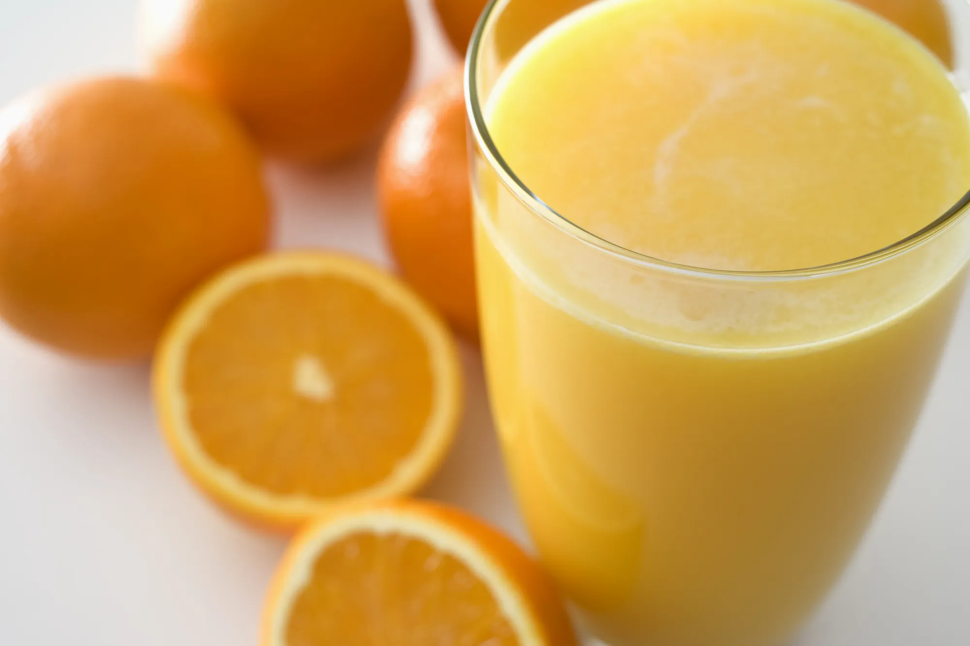 Glass of orange juice and oranges on a white background. Other variations available.