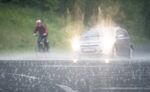 A cyclist rides&nbsp;next to a car while rain pours down in&nbsp;Regensburg on&nbsp;May 11, 2019.