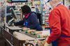 Workers assist a customer at the checkout counter of a Kroger Marketplace store.