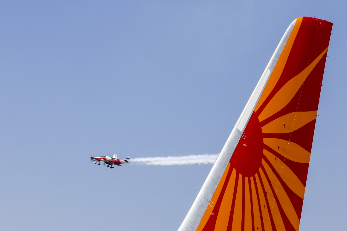 Planes fly past the tail of a Boeing Co. 787 Dreamliner aircraft, operated by Air India Ltd., on display during the India Aviation 2014 air show held at the Begumpet Airport in Hyderabad, India, on Thursday, March 13, 2014. The air show takes place from March 12-16.