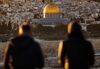 TOPSHOT - Two persons watch the sun setting on the Old City of Jerusalem, with the Muslim mosque of the Dome of the Rock in the center, on January 23, 2017. / AFP / THOMAS COEX (Photo credit should read THOMAS COEX/AFP/Getty Images)