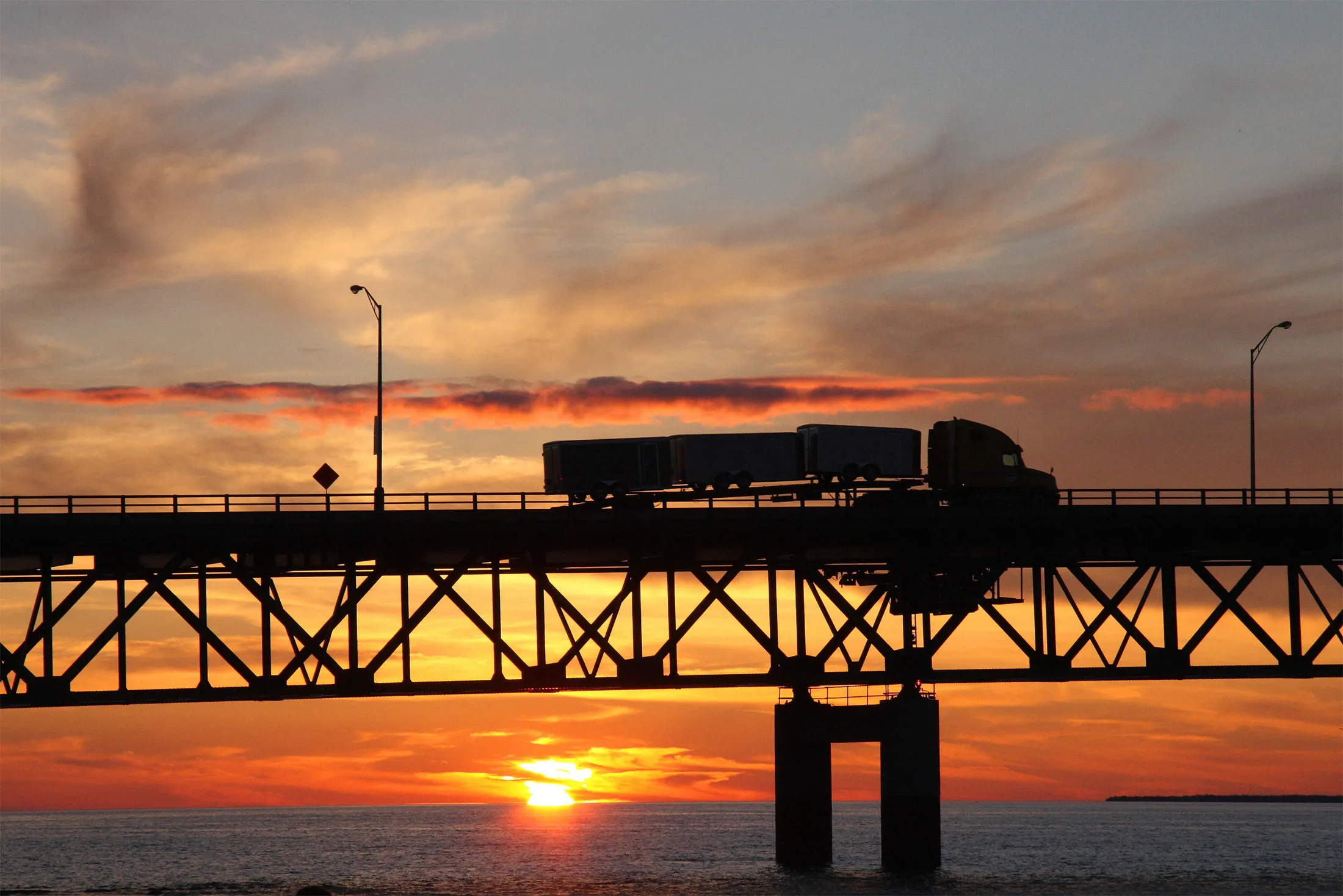 A semi crosses the Mackinaw Bridge as the sun sets over Lake Michigan in Mackinaw City.