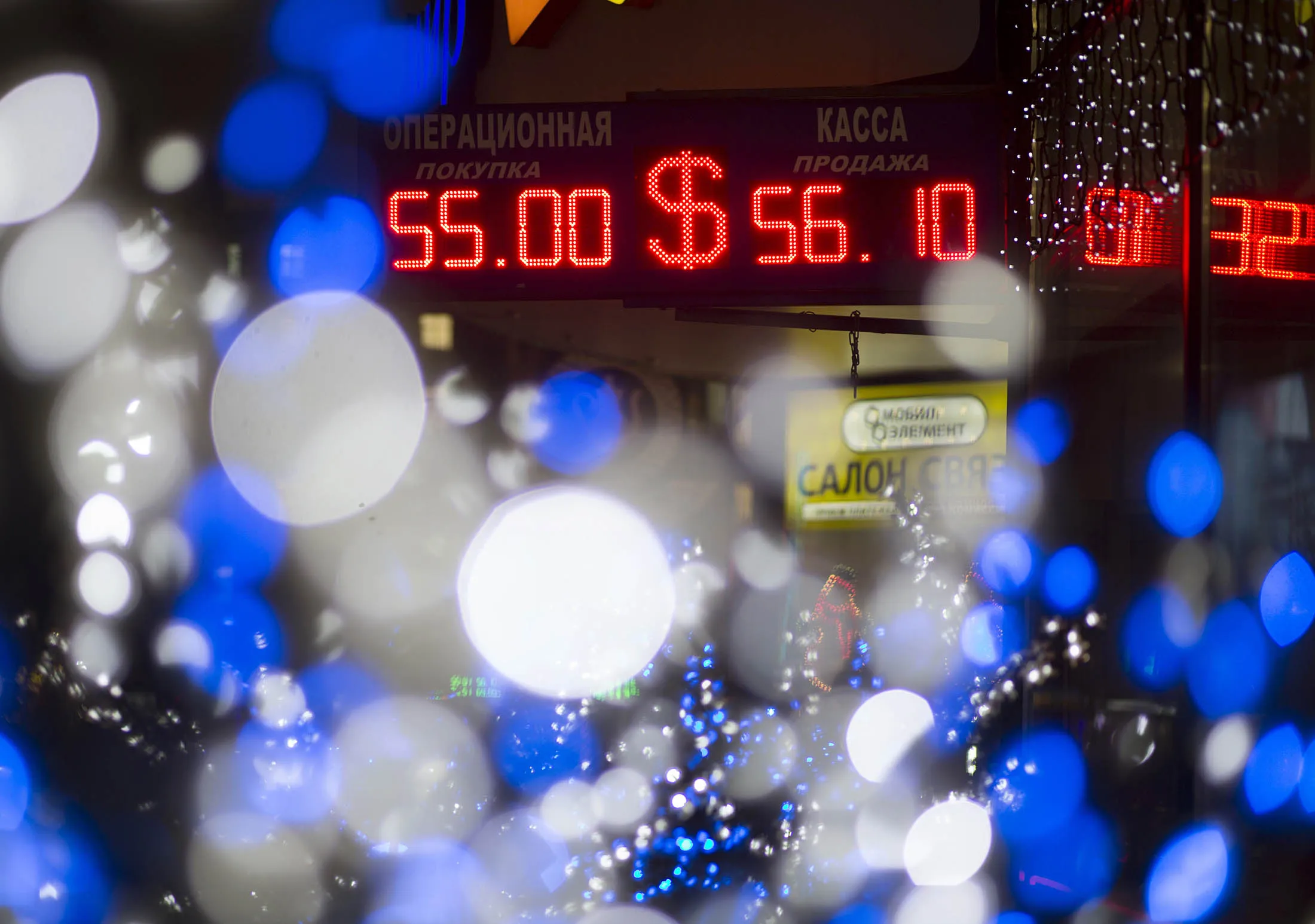An illuminated neon electronic sign displaying a US dollar symbol hangs outside a foreign exchange bureau in Moscow, Russia, on Thursday, Dec. 11, 2014. The ruble tumbled to a record for a second day, spurring speculation Russia's central bank intervened to stem the rout, and bonds slid as weaker oil prices worsen the outlook for an economy verging on recession.
