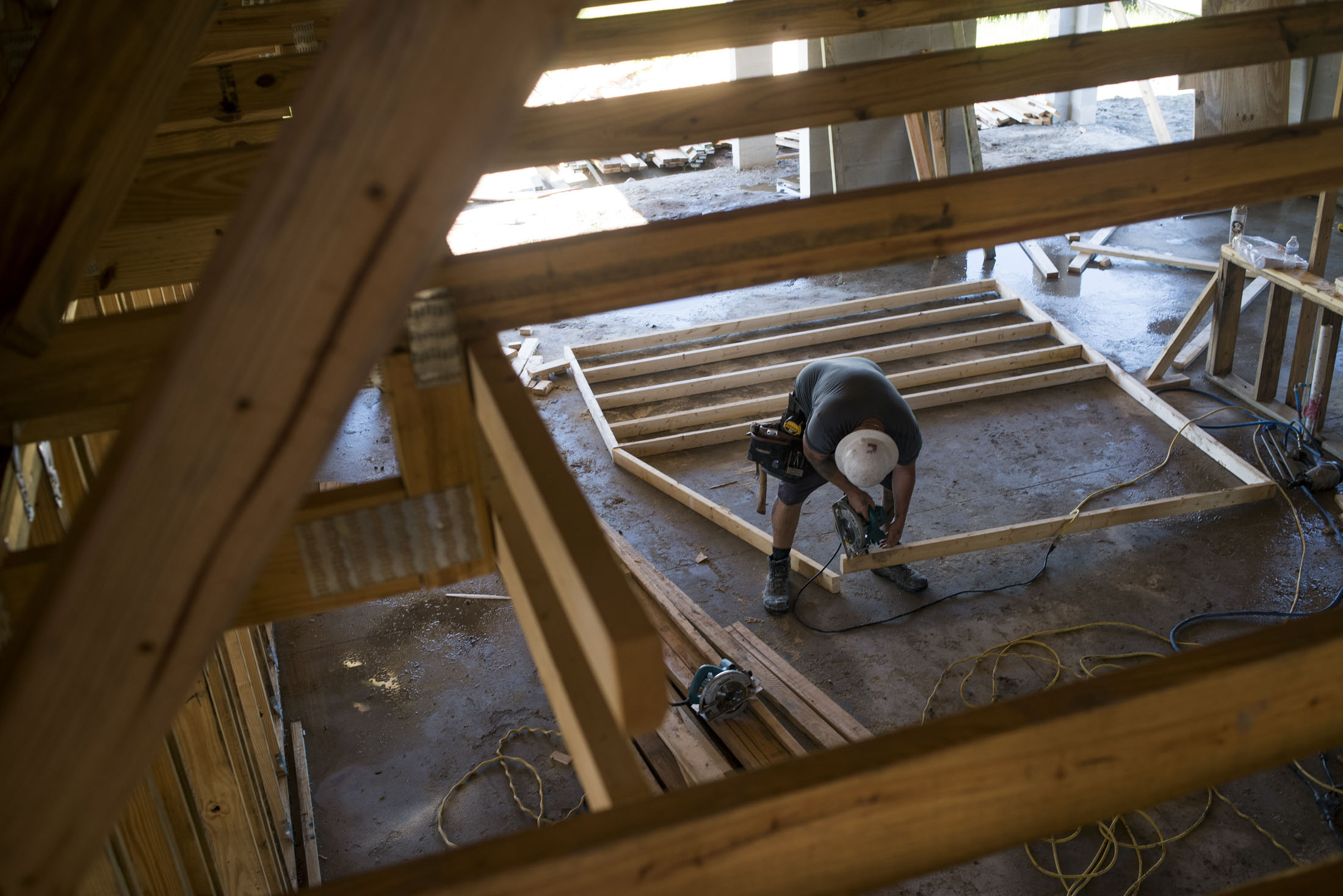 A worker saws a section of lumber inside a home under construction in Ellenton, Florida, U.S., on Thursday, July 6, 2017.