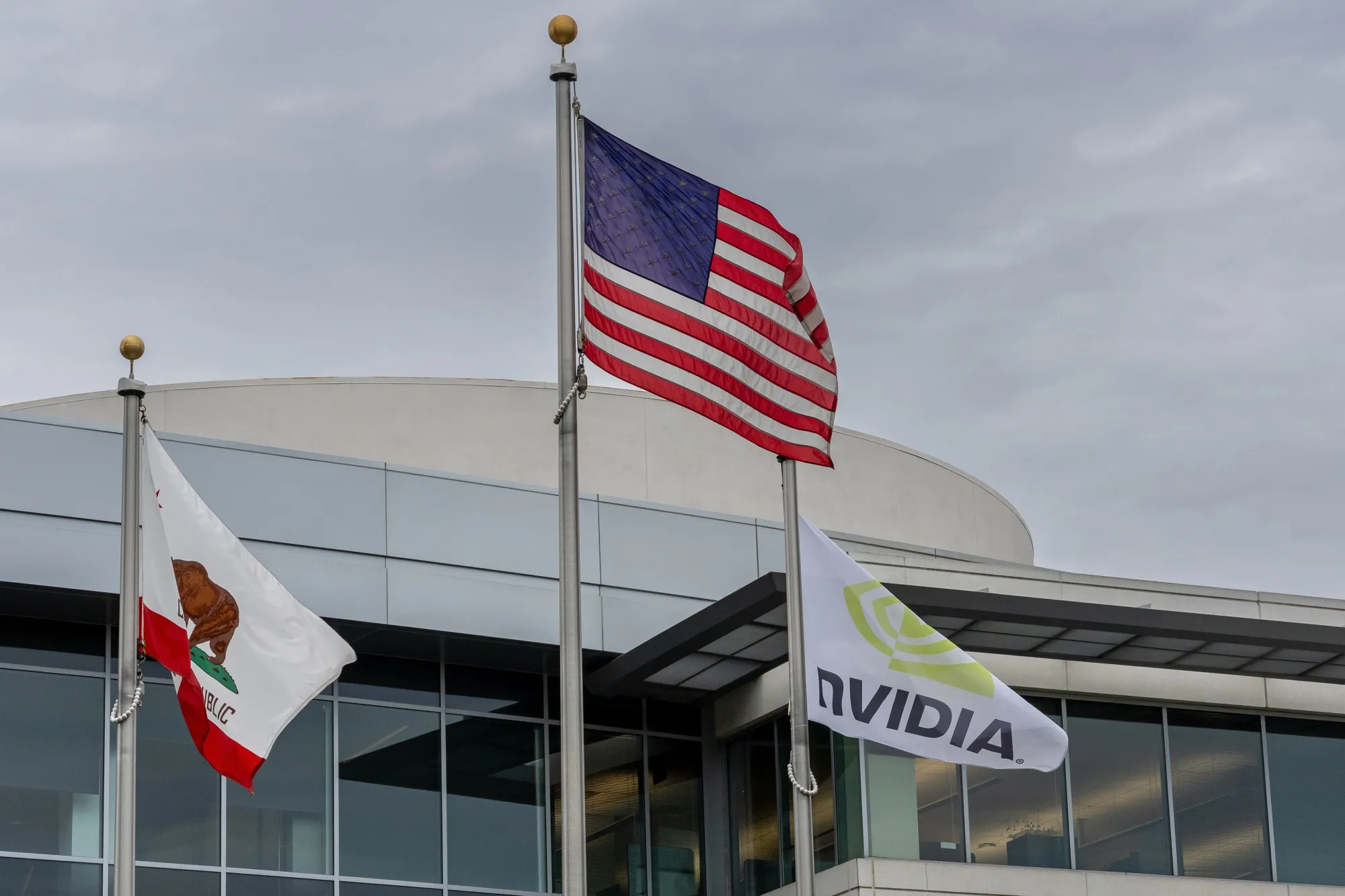 Flags outside the Nvidia headquarters in Santa Clara, California, US, on Thursday, Sept. 18, 2025. Nvidia Corp. agreed to invest $5 billion in Intel Corp. and said the two will co-develop chips for PCs and data centers, a surprise move to help prop up an ailing arch rival that sent Intel shares soaring.