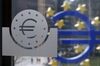 A euro logo, left, sits etched into a glass pane inside the European Central Bank's (ECB) headquarters in Frankfurt.