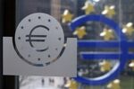 A euro logo, left, sits etched into a glass pane inside the European Central Bank's (ECB) headquarters in Frankfurt.