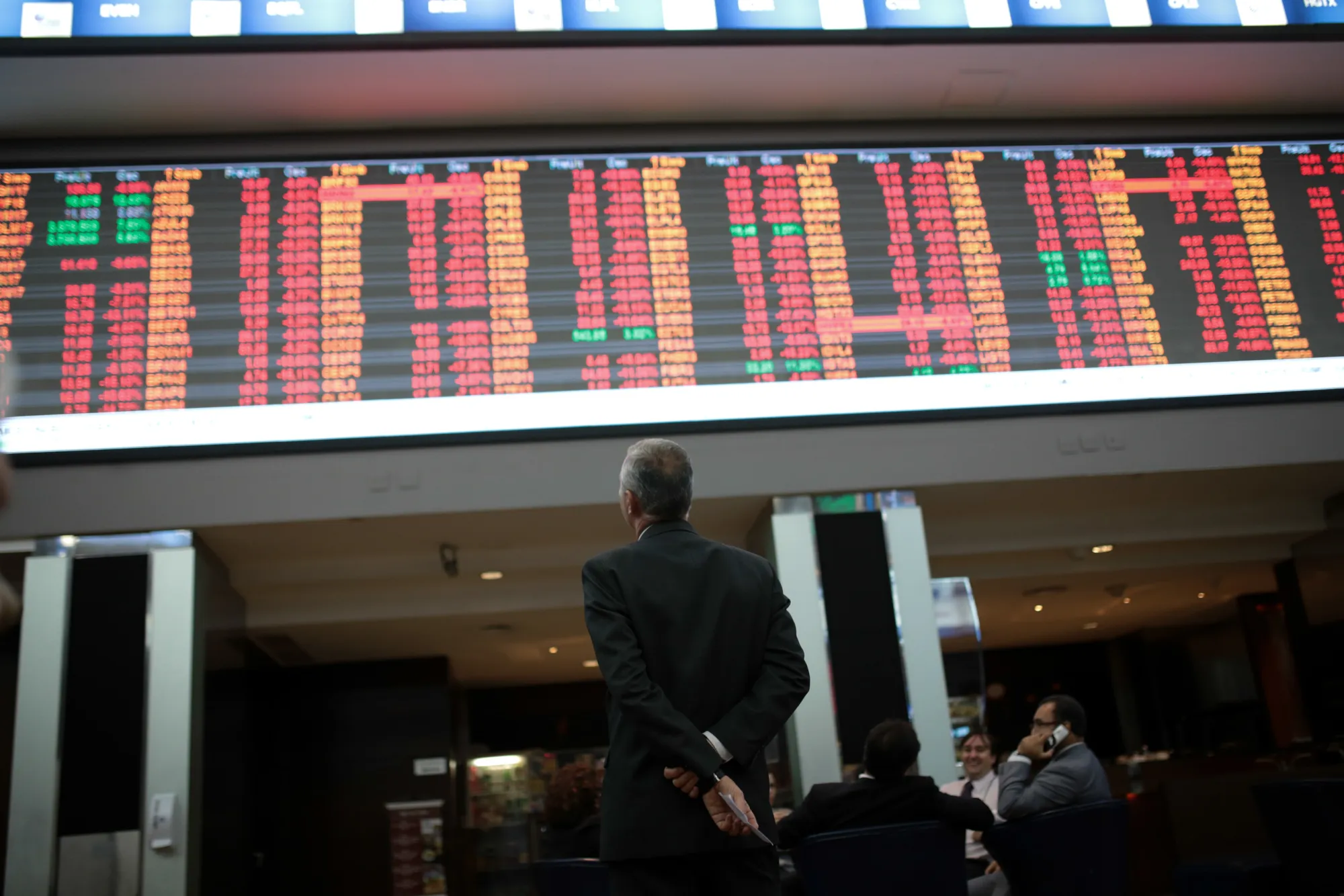 A visitor views the electronic board displaying stock activity at the Brasil Bolsa Bacao stock exchange in Sao Paulo.