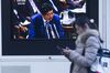 A pedestrian walks past a television screen broadcasting Japan's Prime Minister Shinzo Abe speaking at a parliament in Tokyo, Japan.