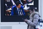A pedestrian walks past a television screen broadcasting Japan's Prime Minister Shinzo Abe speaking at a parliament in Tokyo, Japan.