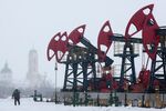 A worker passes a line of oil pumping jacks in an oilfield near Neftekamsk, Russia.