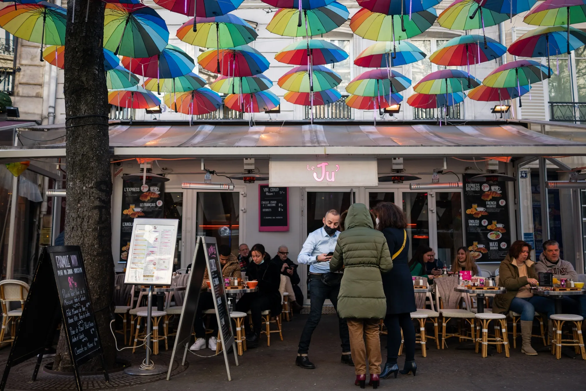 A waiter checks the vaccine pass of customers arriving at a restaurant in central Paris.