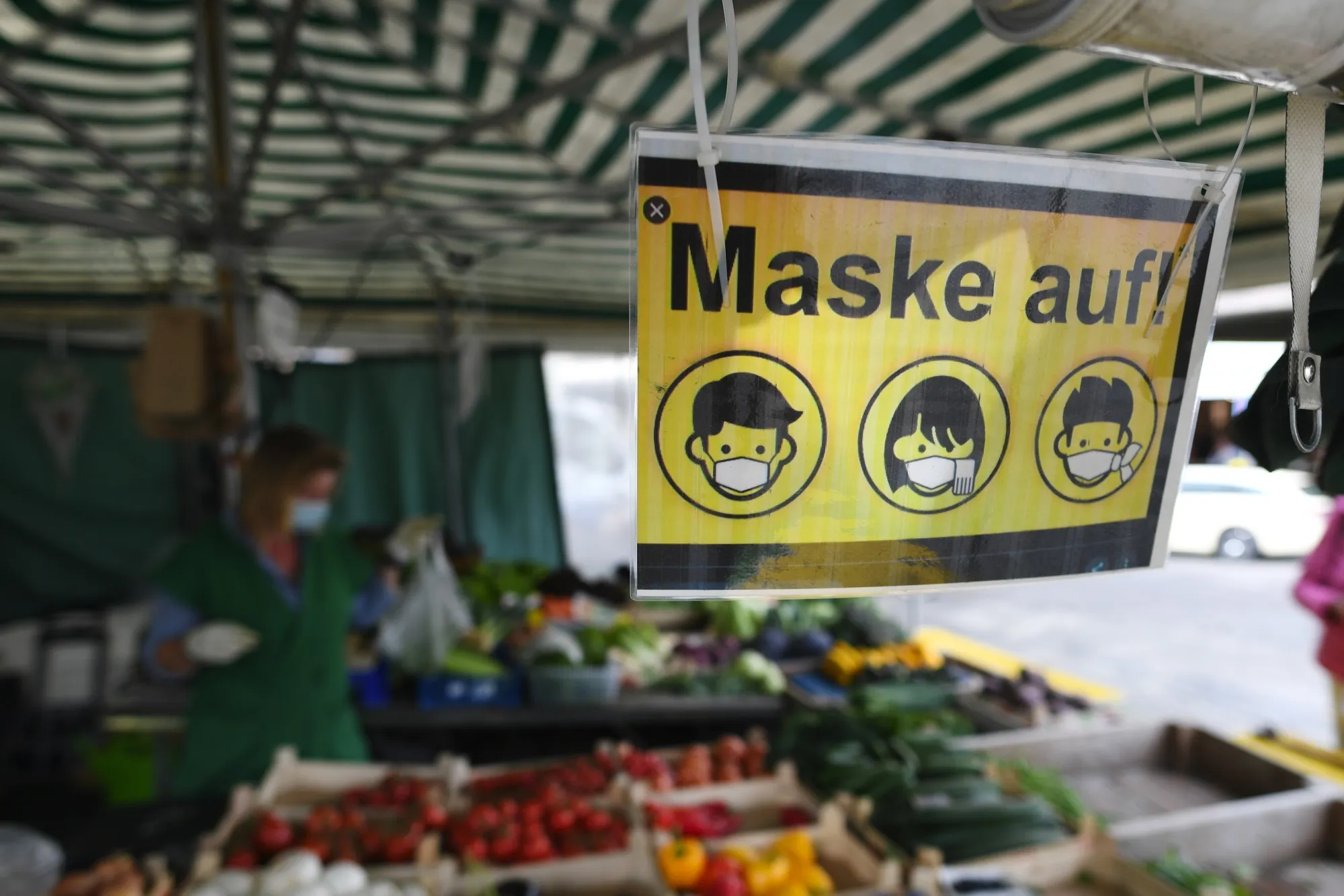 A sign tells customer to put a mask on at a fruit and vegetable stall at Viktualienmarkt in Munich.