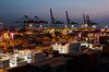 Containers sit stacked beneath gantry cranes at the Sun Kwang Newport Container Terminal (SNCT) at dusk in Incheon New Port in Incheon, South Korea.