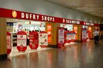 Travelers pass a duty-free store, operated by Dufry AG at Milan airport.