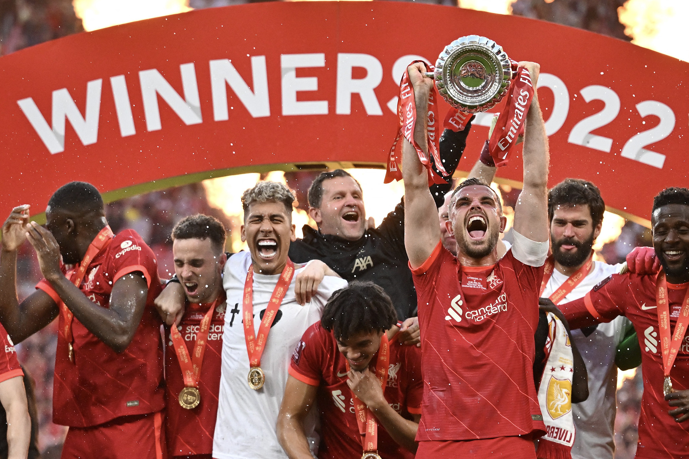Liverpool's midfielder Jordan Henderson&nbsp;holds the trophy while&nbsp;celebrating&nbsp;with teammates after winning the English FA Cup on&nbsp;May 14, 2022.