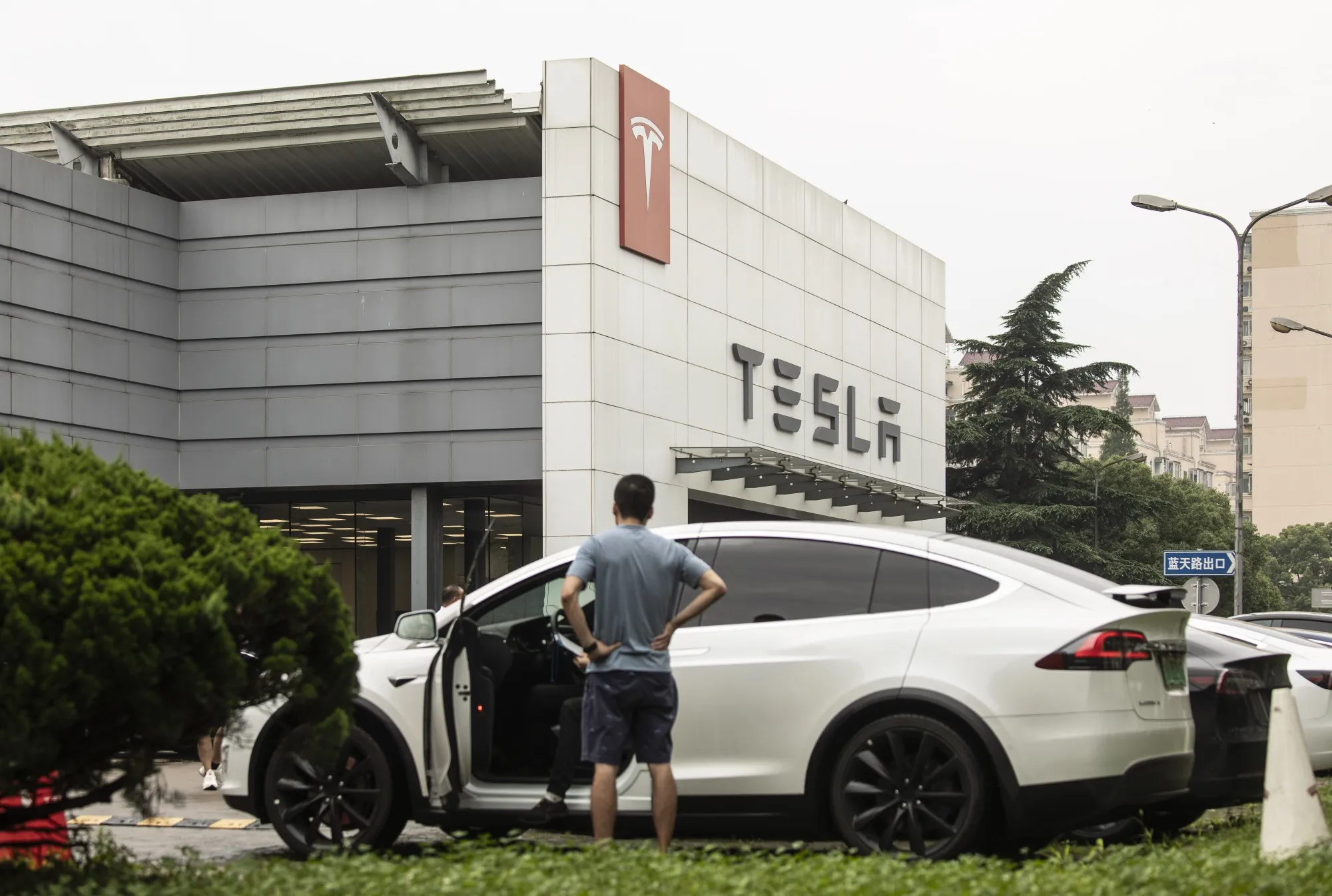 A customer stands in front of Tesla Inc. Model X electric vehicle outside the automaker's dealership in Shanghai.