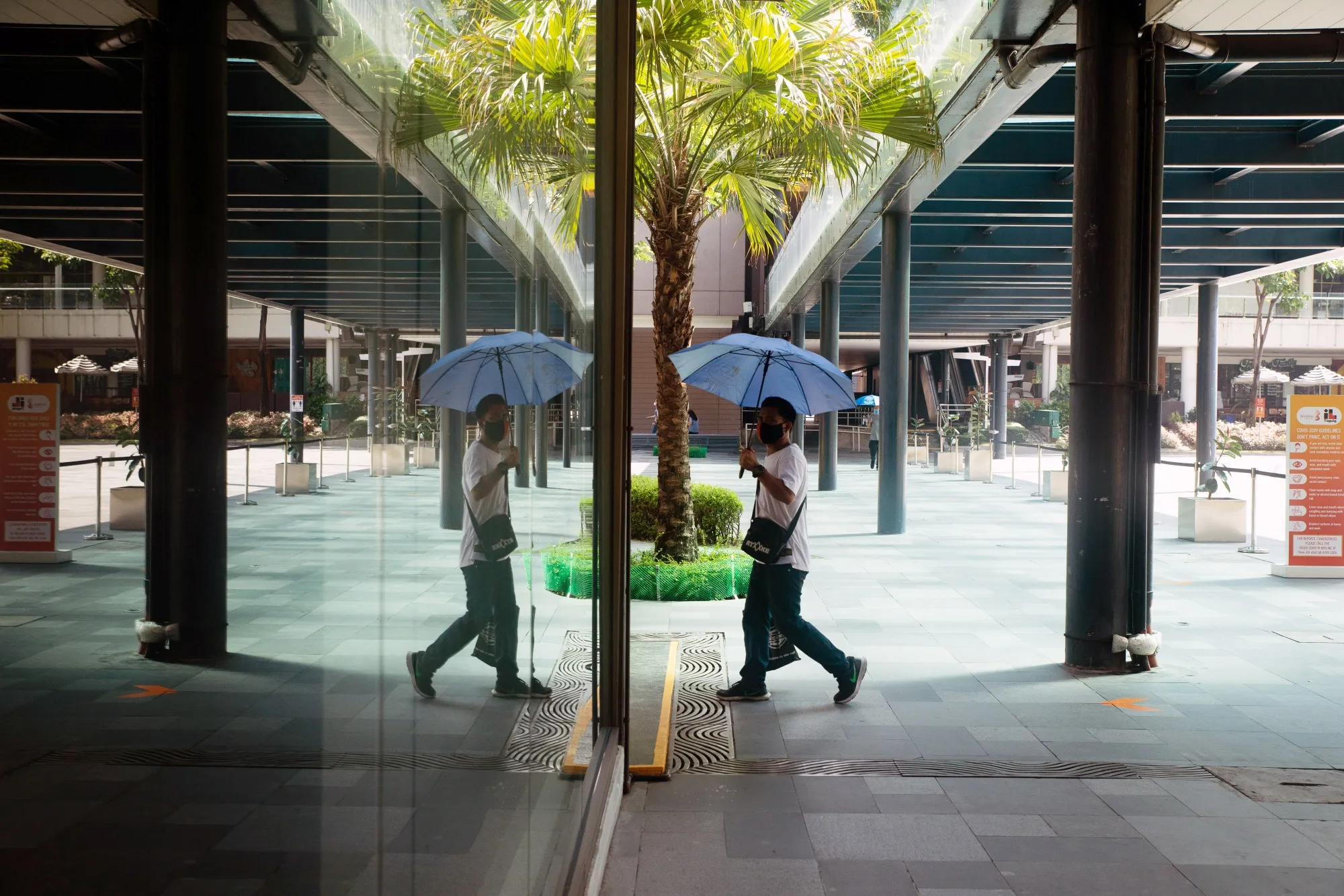 A pedestrian wearing a protective mask walks through a deserted precinct in Bonifacio Global City, Metro Manila, the Philippines,&nbsp;on July 27.